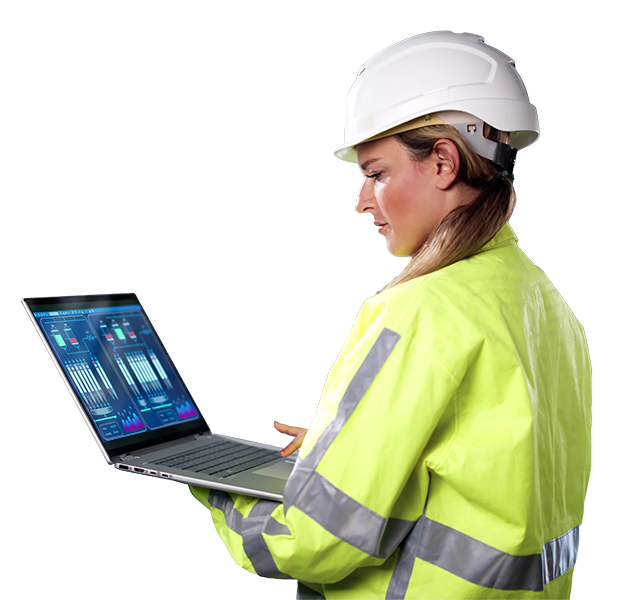 Frau in Sicherheitskleidung und Helm überwacht Maschinen mit Laptop in einer Industrieanlage.